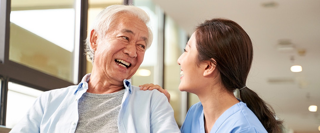 A senior and a nurse laughing together.