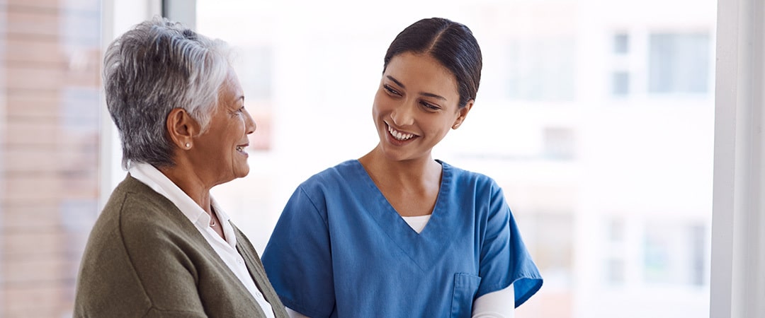 Nurse and resident having a conversation in front of a window